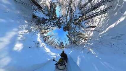 Somewhat bizarre view of a snowmobile captured with a 360-degree camera. The result is an inverted globe effect with the traveller moving through a tunnel of trees.