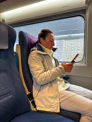 Urban Commute: A Woman Engrossed in Her Smartphone on a Train Journey