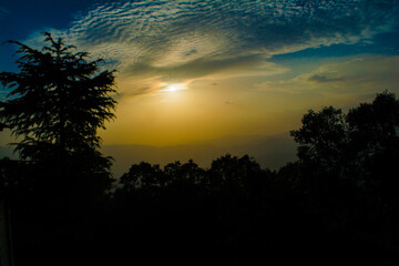 Fototapeta premium Sunset view from the mountains of Lansdowne. Mountain Sunset view in Lansdowne. Amazing golden sunset seen through forest drive, Lansdowne Uttarakhand.