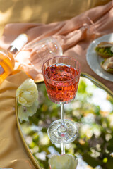 Closeup glass of rose wine , picnic basket, food and flowers on the spring blossom garden. Banner
