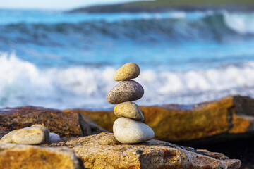 pyramid of stones on the seashore against the background of waves.