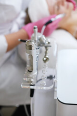 Close-up of Skin Treatment Equipment in Clinic. A clinic's skincare treatment equipment in close-up, with a patient in the background receiving a procedure