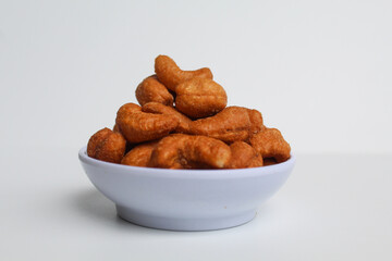 Cashew nut in a white small bowl. isolated on white background, side view