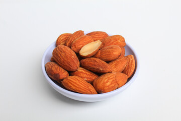 Roasted almond in small white bowl, isolated on white background