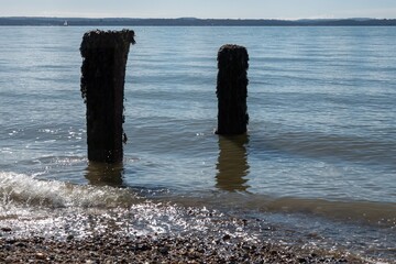 gentle waves lapping old wooden groynes in the sea at Browndown Hampshire England