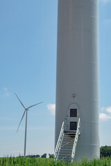 Stairs leading to main entrance of tall windmill tower with rotor blades. Wind turbine with...