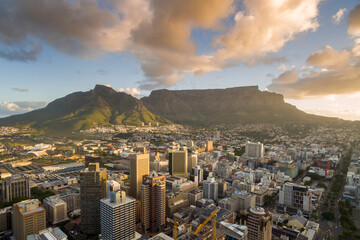 An aerial view of Cape Town central business district in late afternoon as the sun is setting, showing Table Mountain.