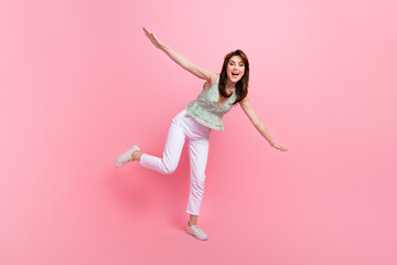 Full length photo of adorable good mood girl having fun flying open hands isolated on pink color...