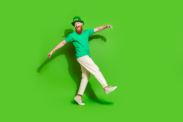 Fototapeta na wymiar Full length profile portrait of excited cheerful guy dance walk empty space isolated on green color background