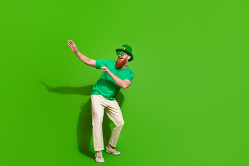 Full size photo of crazy overjoyed man have fun dancing empty space isolated on green color...