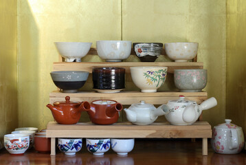 Ceramic sets displayed on wooden shelves.