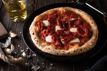 Pizza with mozzarella and sun-dried tomatoes with a glass of white wine. Side view.