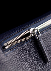 Part of a blue leather bag on a black background. Leather goods.