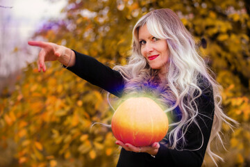 Halloween a woman with gray hair holds a magical glowing pumpkin against the background of an...