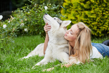 Young blond woman with dog Husky on grass in summer park
