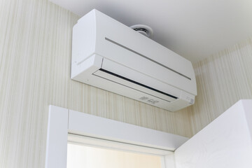 Air-conditioning, attached to wall, hanging over entrance door to apartment