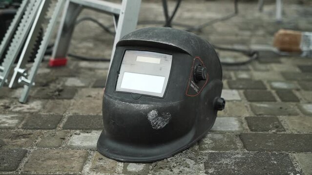 Black Welding Helmet lies on a concrete tile at a construction site