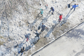 8 Residents of high-rise building clean area of yard with snow, above view