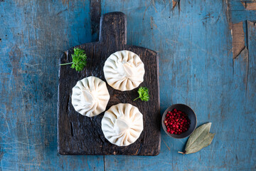 Raw khinkali dumplings with meat. Blue background.