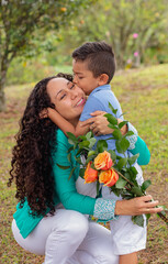 Vertical Photo of Mother's Day Affection: Son Giving a Kiss and Flowers to His Happy Mom
