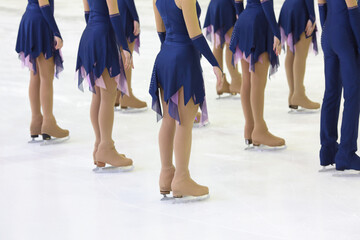 Skaters in beautiful costumes and skates on the ice in the sports complex, view below waist