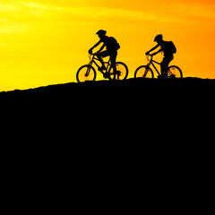Mountain Biking Riders Silhouetted on Ridge with Mountains