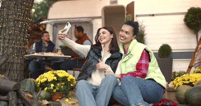Happy girls sitting outside a van taking a selfie