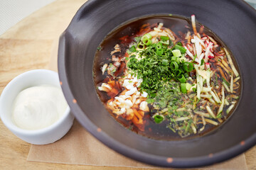 Plate of vegetable soup and bowl with sauce.