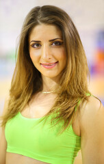 Portrait of beautiful girl cheerleader in a light green suit in the gym