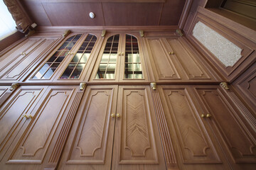 Facade of a wooden bookcase with glass inserts, the view from the bottom up