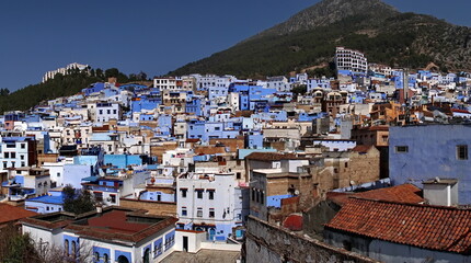 Fototapeta na wymiar Blue and white buildings in the medina, on the side of a hill, in Chefchaouen, Morocco