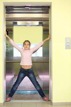 Girl in jeans holding the elevator door and kicking