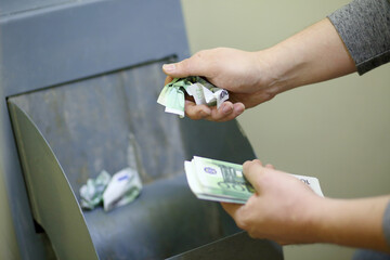 Man crumples fake banknotes and throws them in the garbage disposal