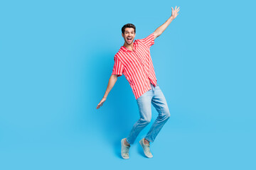 Fototapeta premium Full body photo of overjoyed guy wear stylish shirt jeans trousers stand on tiptoes arms show big sale isolated on blue color background