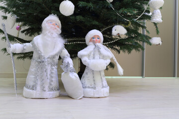 Toy statuettes Snow Maiden and father frost under Christmas tree, close-up