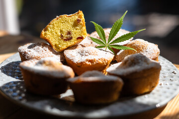 Cupcakes with cannabis leaf on plate. Dessert cake with marijuana close up. Cooking baking cakes with medical weed. Food photography
