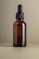 Dark brown glass bottle with dropper pipette with serum or essential oil on a beige background. Skincare cosmetic Beauty concept for face body care. Place for text.