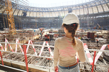 Girl in a helmet watching the reconstruction of the stadium