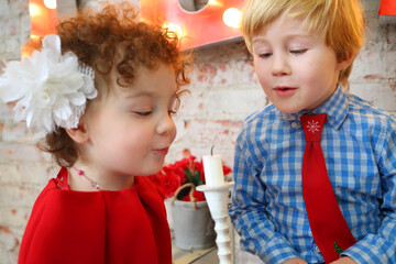 Little happy girl and boy blow out white candle, focus on boy