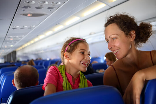 Mother and daughter smiling at each other on an airplane