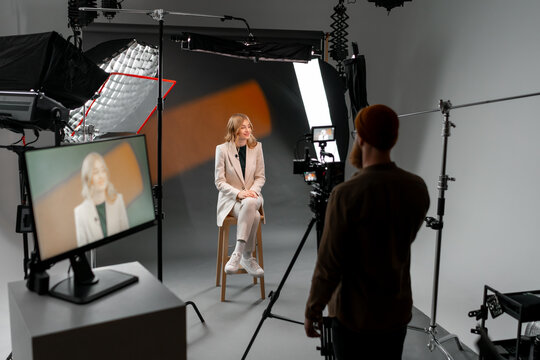 Photographer capturing woman on stool in studio