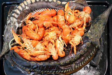 Baked sturgeons and crayfish on a black pan, close-up