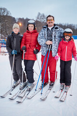 Family portrait of four skiers standing at ski resort in evening