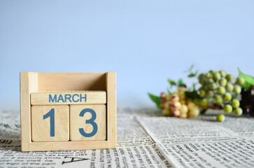 March 13, Calendar cover design with number cube with fruit on newspaper fabric and blue...