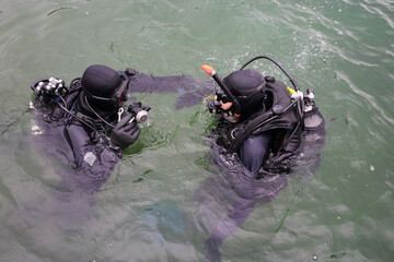 Two men with modern equipment dive in water of river, top view