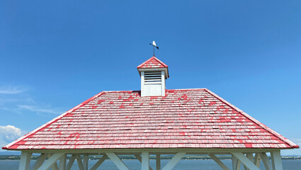 Faded red wooden roof with bell tower and weather vane to indicate wind direction. Pergolas in a...