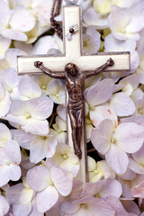 Prayer beads on flowers. Crucifix with Jesu. Catholic sympbol.