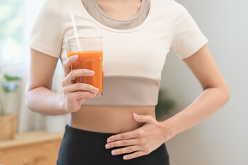Orange detox juice, good digestive, young woman hand on stomach, belly with glass of vegetable...