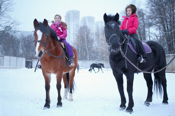 Two girls sitting on horseback at the equestrian site near the residential complex