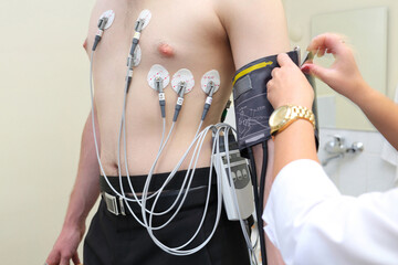 �atient with ECG electrodes on chest and an instrument for measuring blood pressure, motion blur